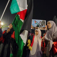 Des personnes brandissant des pancartes et des drapeaux palestiniens lors d'une manifestation à Tripoli, capitale de la Libye, le 17 octobre 2023. (Crédit : Mahmud Turkia/AFP)