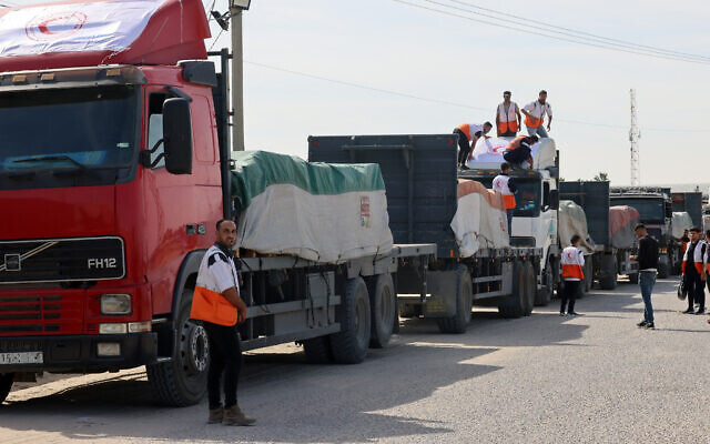 Des employés du Croissant-Rouge palestinien déchargeant des camions transportant de l'aide humanitaire après leur entrée dans la bande de Gaza depuis l'Égypte via le poste-frontière de Rafah, le 21 octobre 2023. (Crédit : Saïd Khatib/AFP)