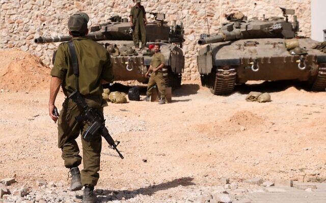 Des soldats israéliens rassemblés près de chars Merkava alors qu'ils occupent une position à un endroit non divulgué à la frontière avec le Liban, le 22 octobre 2023. (Crédit : Jalaa Marey/AFP)