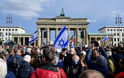 Des manifestants arborent des drapeaux israéliens lors d'un rassemblement de solidarité avec Israël à Berlin, le 22 octobre 2023. (Crédit : John MACDOUGALL / AFP)