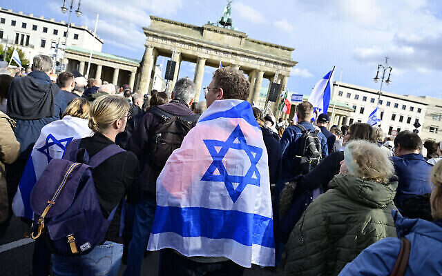 Un homme se couvre du drapeau israélien pour assister à un rassemblement en soutien à Israël. Berlin, en Allemagne, le 22 octobre 2023. (Photo de John MACDOUGALL / AFP)