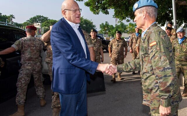 Le Premier ministre intérimaire du Liban, Najib Mikati (G), serre la main du chef de mission de la FINUL, le général Aroldo Lazaro Saenz, au quartier général de la force de maintien de la paix dans la ville frontalière de Naqura, au sud du Liban, le 24 octobre 2023. (Crédit : UNIFIL/AFP)