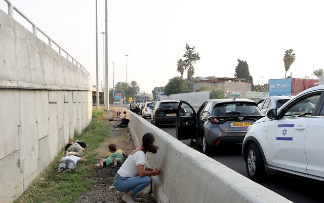 Des personnes quittant leur véhicule pour se mettre à l'abri lors d'une attaque de roquettes palestiniennes depuis la bande de Gaza, le long de l'autoroute Ayalon, à Tel Aviv, le 24 octobre 2023. (Crédit : Gil Cohen-Magen/AFP)
