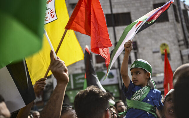 Des personnes brandissant des drapeaux de groupes palestiniens lors d'une marche de solidarité avec la population de la bande de Gaza, dans la ville de Ramallah, en Cisjordanie, le 27 octobre 2023. (Crédit : Aris Messinis/AFP)