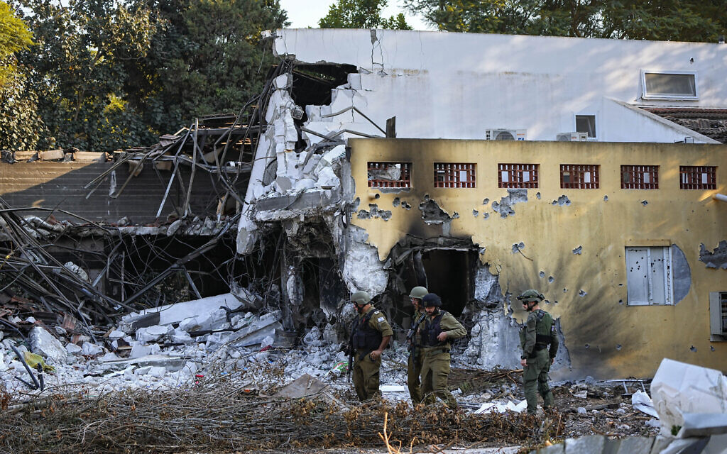 Des soldats israéliens passent devant des maisons détruites par des terroristes du Hamas dans le kibboutz Beeri, le 14 octobre 2023. (Crédit : AP Photo/Ariel Schalit)