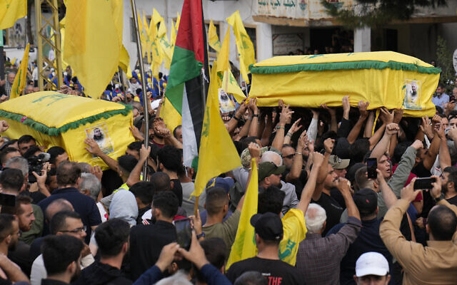 Des partisans du Hezbollah portant les cercueils de deux terroristes tués par des bombardements israéliens, lors de leur procession funéraire dans le village de Kherbet Selem, au sud du Liban, le 10 octobre 2023. (Crédit : Hussein Malla/AP Photo)