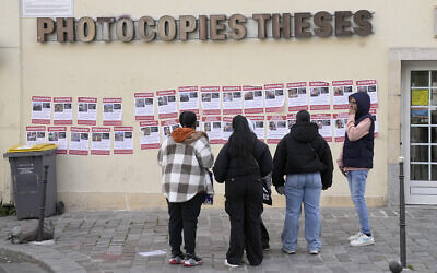 Des personnes regardant des images montrant des otages détenus par des terroristes à Gaza, sur des affiches accrochées par l'UEJF (Union des étudiants juifs de France), à Paris, en France, le 16 octobre 2023. (Crédit : Michel Euler/AP Photo)