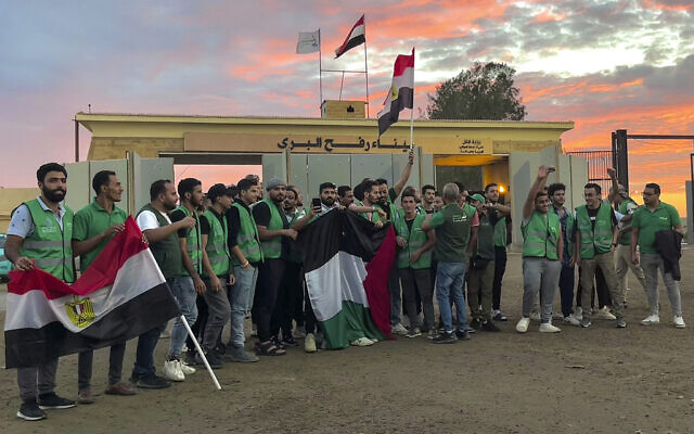 Des membres d'un convoi d'aide humanitaire pour la bande de Gaza brandissent des drapeaux égyptiens et palestiniens au point de passage de Rafah, en Égypte, le 17 octobre 2023. (Crédit : AP Photo/Omar Aziz)