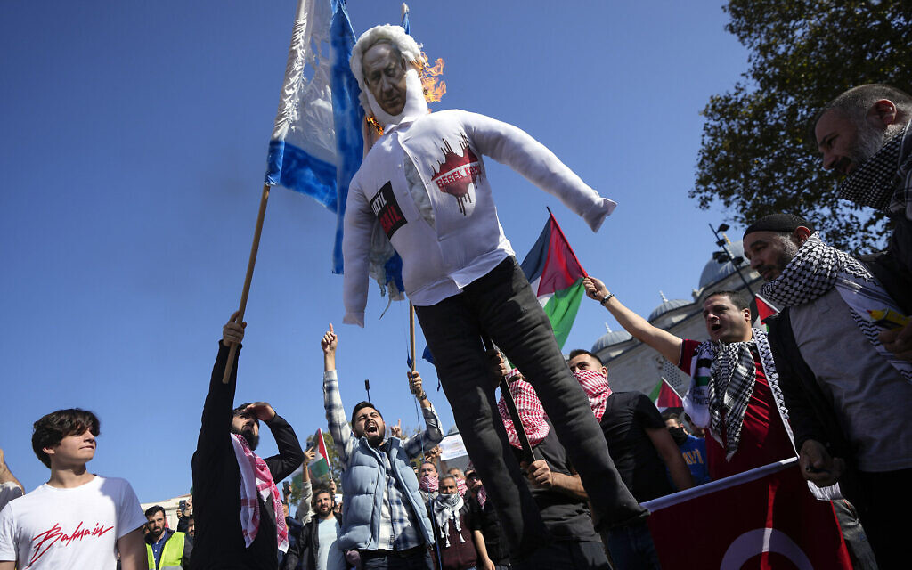 Des manifestants scandant des slogans tout en brûlant une poupée avec une photo du Premier ministre Benjamin Netanyahu et un simulacre de drapeau israélien lors d'une manifestation de solidarité avec les Palestiniens dans le cadre de la guerre entre Israël et le groupe terroriste Hamas, qui dirige la bande de Gaza, à Istanbul, en Turquie, le 20 octobre 2023. (Crédit : Khalil Hamra/AP Photo)