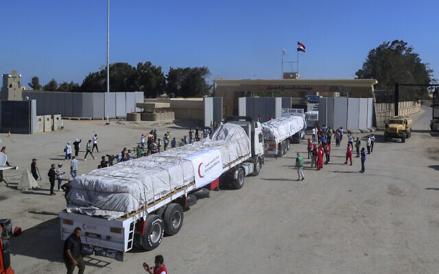 Des camions du Croissant Rouge égyptien transportant de l'aide humanitaire pour la bande de Gaza traversant la frontière de Rafah, à Rafah, en Égypte, le 21 octobre 2023. (Crédit : Mohammed Asad/AP Photo)