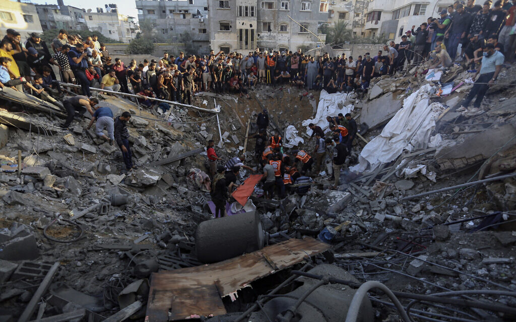 Les Palestiniens rassemblés devant les restes d'une maison détruite suite aux frappes aériennes israéliennes sur la ville de Gaza, le 21 octobre 2023. (Crédit : Abed Khaled/AP Photo)