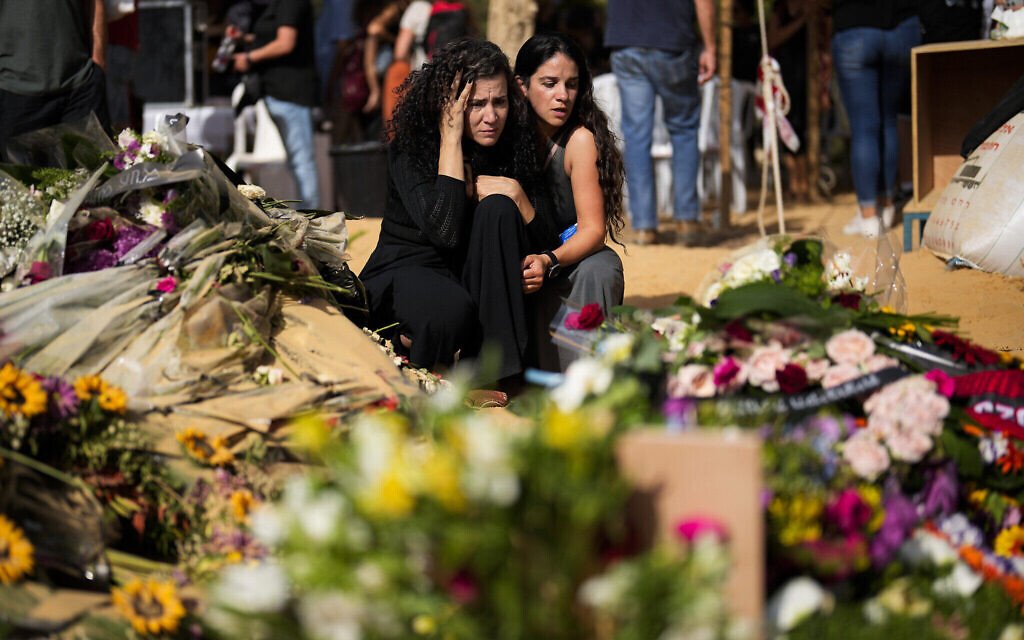 Des personnes en deuil assistant aux funérailles de David Caroll tué au kibboutz Beeri par des terroristes du Hamas le 7 octobre, au kibboutz Revivim, dans le sud d'Israël, le 22 octobre 2023. (Crédit : Francisco Seco/AP Photo)