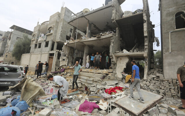Des Palestiniens inspectent les dommages causés aux bâtiments détruits par les frappes aériennes israéliennes à Rafah, le 29 octobre 2023. (Crédit : AP Photo/Hatem Ali)