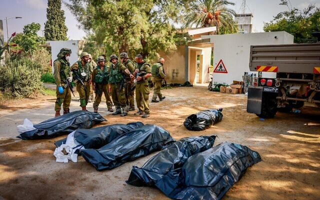 Des soldats israéliens enlevant les corps de civils israéliens dans le kibboutz Kfar Azza, près de la frontière entre Israël et Gaza, dans le sud d'Israël, le 10 octobre 2023. (Crédit : Chaïm Goldberg/Flash90)