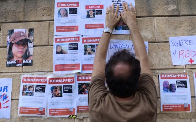 Des familles accrochent des affiches montrant les personnes prises en otage par les terroristes de Gaza, aux abords du ministère de la Défense à Tel Aviv, le 14 octobre 2023. (Crédit : Tomer Neuberg/FLASH90)