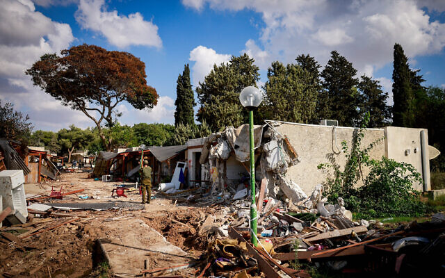 Des soldats israéliens autour des destructions causées par les terroristes du Hamas dans le kibboutz Kfar Azza, près de la frontière entre Israël et la bande de Gaza, dans le sud d'Israël, le 15 octobre 2023. (Crédit : Chaïm Goldberg/Flash90)