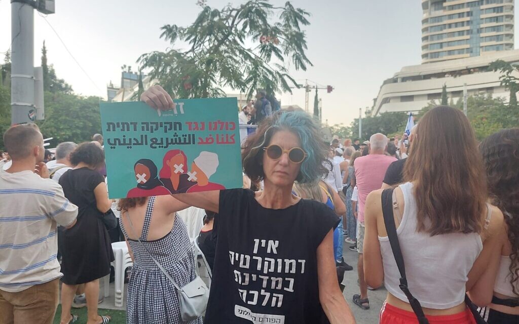 Shoham Smith protestant contre la séparation des sexes lors de la prière de Yom Kippour à Tel Aviv, le 25 septembre 2023. Sur son t-shirt, on peut lire : "Il n'y a pas de démocratie dans un État halakhique" et sur la pancarte : "Nous sommes tous contre la législation religieuse" en hébreu et en arabe. (Autorisation)