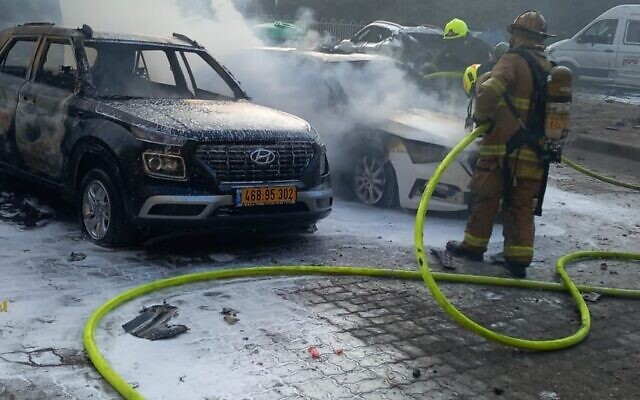 Des pompiers éteignent l'incendie d'une voiture causé par l'impact d'une roquette à Ashdod, le 31 octobre 2023. (Crédit : Services d'incendie et de secours)