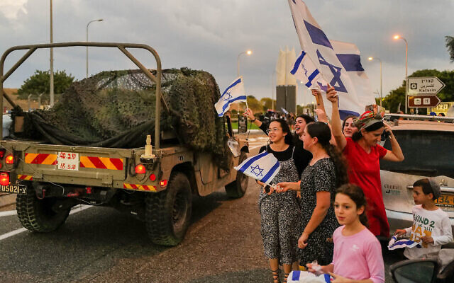 Des Israéliens brandissant le drapeau national en signe de soutien aux forces de sécurité israéliennes, dans la ville de Katsrin, dans le nord du pays, sur le plateau du Golan, le 11 octobre 2023. (Crédit : Michael Giladi/Flash90)