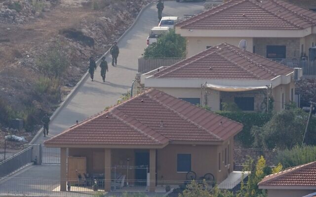 Des soldats israéliens se déployant entre les maisons de la ville israélienne de Metula, vue du côté libanais de la frontière israélo-libanaise dans le village méridional de Kfar Kila, au Liban, le 8 octobre 2023. (Crédit : Hussein Malla/ AP Photo)
