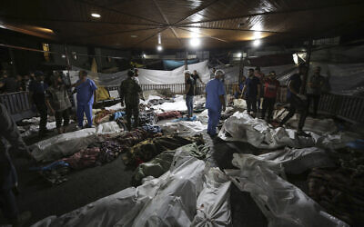 Les corps des Palestiniens tués par une explosion à l'hôpital Ahli Arab sont rassemblés dans la cour de l'hôpital al-Shifa, dans la ville de Gaza, au centre de la bande de Gaza, le 17 octobre 2023. Israël a affirmé que l'explosion avait été causée par un tir de roquette raté par des terroristes palestiniens, réfutant les affirmations du Hamas selon lesquelles il s'agirait d'une attaque aérienne israélienne (Crédit : Abed Khaled/AP)