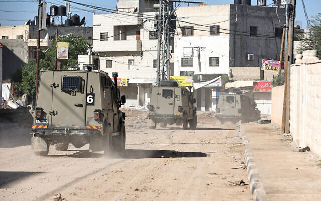 Des véhicules militaires israéliens patrouillent dans le camp de réfugiés de Jénine, en Cisjordanie, le 29 novembre 2023, lors d'une opération militaire dans le camp. (Crédit : Zain JAAFAR / AFP)