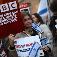 Des manifestants brandissant des pancartes et drapeaux israéliens à un rassemblement devant le siège de la BBC (British Broadcasting Corporation) pour tenter de la convaincre de qualifier le Hamas de « terroriste », à Londres, le 16 octobre 2023. (Crédit : Daniel Leal/AFP)