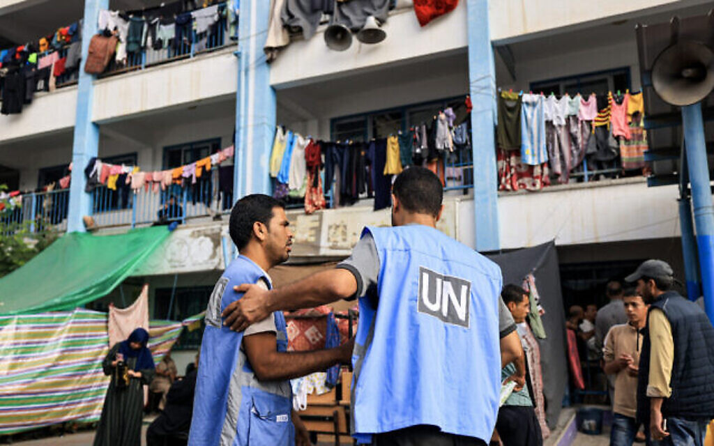 Des employés de l'agence de l'Office de secours et de travaux des Nations unies pour les réfugiés de Palestine (UNRWA) discutant dans la cour de récréation d'une école gérée par l'UNRWA et transformée en abri pour les Palestiniens déplacés à Khan Yunis, dans le sud de la bande de Gaza, le 25 octobre 2023. (Crédit : Mahmud Hams/AFP)