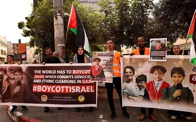 Des Palestiniens brandissent des affiches demandant le boycott des produits israéliens lors d'un rassemblement dans la ville de Hébron en Cisjordanie, le 28 octobre 2023. (Crédit : HAZEM BADER / AFP)