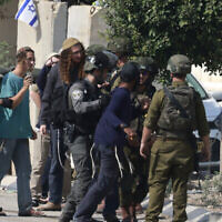 Des soldats israéliens retenant des résidents d'implantations après qu'ils ont pris d'assaut le village palestinien de Dayr Sharaf à la suite d'une attaque terroriste au cours de laquelle un conducteur israélien a été abattu, en Cisjordanie, le 2 novembre 2023. (Crédit : Jaafar Ashtiyeh/AFP)