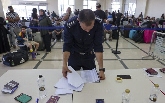 Un garde-frontière palestinien vérifie les documents des personnes ayant la double nationalité et des étrangers alors qu'ils attendent de traverser le poste frontière de Rafah avec l'Égypte, dans le sud de la bande de Gaza, le 7 novembre 2023. (Crédit : Mohammed ABED / AFP)