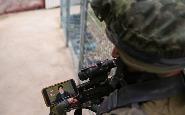 Un soldat israélien regarde un discours télévisé du leader du Hezbollah Hassan Nasrallah, à proximité de la frontière libanaise, le 11 novembre 2023. (Crédit : Jalaa Marey/AFP)