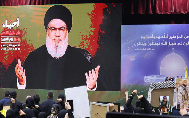 Des partisans du groupe terroriste chiite libanais du Hezbollah regardant le chef Hassan Nasrallah prononcer un discours télévisé sur grand écran, dans une salle de Beyrouth, le 11 novembre 2023. (Crédit : Anwar Amro/AFP)