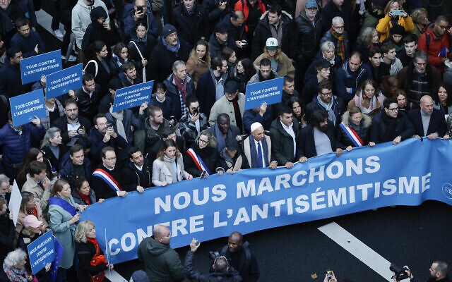 L'écrivain, artiste et militant des droits de l'homme français d'origine polonaise Marek Halter (4eD) et des représentants politiques défilent sous une banderole intitulée "Nous marchons contre l'antisémitisme", à Paris, le 12 novembre 2023. (Crédit : Geoffroy Van der Hasselt / AFP)