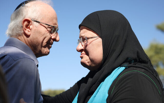 Nir (gauche), le frère de la militante pacifiste israélo-canadienne Vivian Silver, salue Ghadir Hani, une autre militante pacifiste d'Akko, lors de la cérémonie commémorative au kibboutz Gezer, dans le centre d'Israël, le 16 novembre 2023. (Crédit : Oren ZIV / AFP)