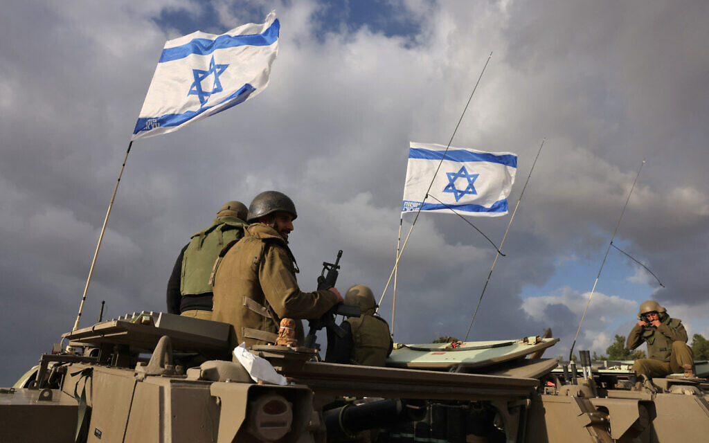 Des soldats israéliens assis sur des véhicules blindés alors qu'ils se déploient près de la frontière entre le sud d'Israël et la bande de Gaza, le 20 novembre 2023. (Crédit :  Menahem Kahana/AFP)