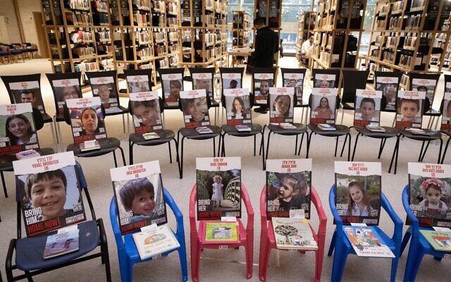 A picture taken on November 21, 2023 at the new building of the National Library of Israel in Jerusalem, shows an installation consisting of chairs with books and portraits of Israeli hostages taken by Palestinian Hamas militants during the October 7 attack. (Photo by Kenzo TRIBOUILLARD / AFP)