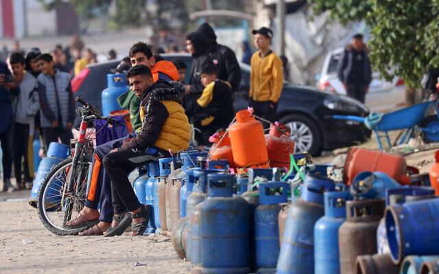 Des Palestiniens attendent avec des bouteilles vides l'arrivée de gaz domestique dans un camion citerne entré dans la bande de Gaza depuis l'Égypte au poste-frontière de Rafah, le 25 novembre 2023. (Crédit : SAID KHATIB / AFP)
