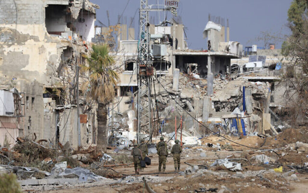 Des soldats israéliens passent devant des bâtiments détruits, le long de la route Salaheddine qui relie le nord de la bande de Gaza au sud dans le quartier de Zeitoun, à la périphérie de la ville de Gaza, le 28 novembre 2023. (Crédit : Mahmoud Hams/ AFP)