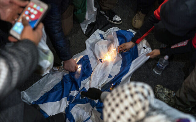 Des manifestants pro-palestiniens brûlent un drapeau israélien lors d'une marche appelant à un cessez-le-feu à Gaza, le 10 novembre 2023, à New York. (Crédit : AP/Eduardo Muñoz Álvarez)