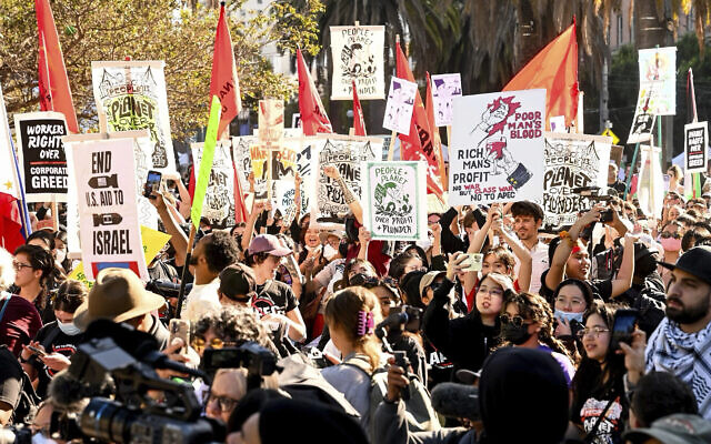 Des manifestants brandissent des pancartes, notamment contre l'aide militaire américaine à Israël, alors qu'ils défilent contre le sommet de l'APEC, le 12 novembre 2023, à San Francisco. (Crédit : AP Photo/ Noah Berger)