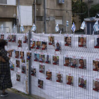 Une femme regarde les photos d’otages détenus à Gaza, exposées à Ramat Gan, le 22 novembre 2023. (Photo AP/Oded Balilty)