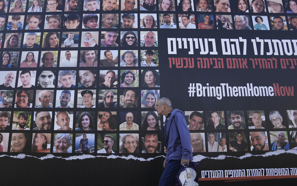 Un homme passant devant un panneau d'affichage demandant le retour des 240 otages enlevés lors de l'attaque terroriste du Hamas en Israël le 7 octobre, à Jérusalem, le 24 novembre 2023. (Crédit : Mahmoud Illean/AP Photo)