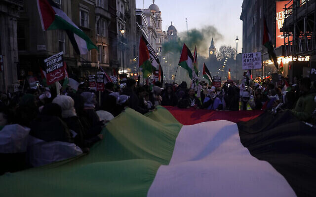 Des manifestants brandissent des drapeaux et des pancartes alors qu’ils participent à une manifestation pro-palestinienne et anti-israélienne près de Trafalgar Square à Londres, le samedi 25 novembre 2023. (Crédit : Alberto Pezzali/AP)