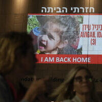 Des gens passant devant une photo d'Avigaïl Idan, 4 ans, une otage détenue par le Hamas pendant 51 jours qui a été libérée, projetée sur un bâtiment à Tel Aviv, le 26 novembre 2023. (Crédit : Ariel Schalit/AP Photo)