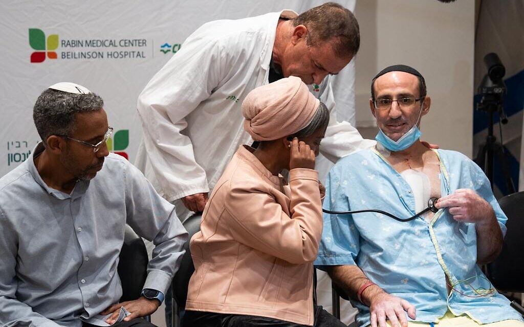 Ayelet Samo, avec son époux Moshe, à gauche, utilise un stéthoscope pour entendre le cœur de son fils battre dans la poitrine de Yaakov Malka à l'hôpital Beilinson, le 20 novembre 2023. (Autorisation : Hôpital Beilinson)