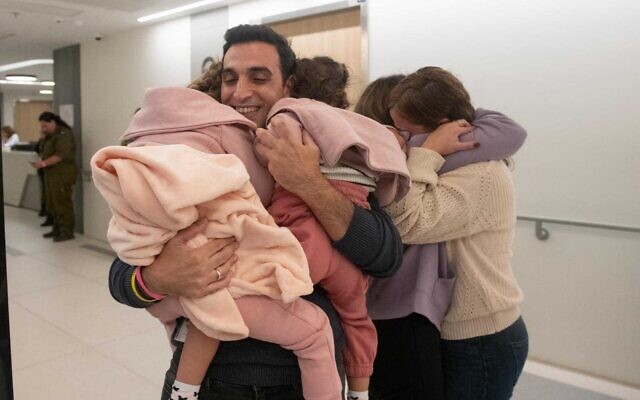 Yoni Asher embrassant ses filles Raz et Aviv, prises en otages par le Hamas, à leur libération, le 24 novembre 2023. (Crédit : Armée israélienne)