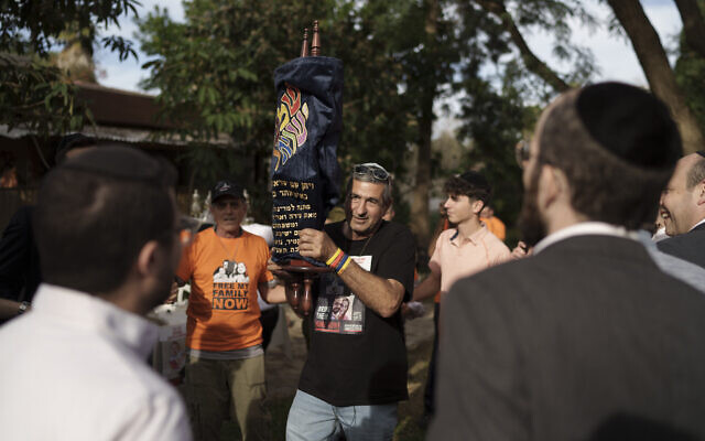 Eli Bibas tient un rouleau de la Torah qui a survécu à la Shoah lors d'une cérémonie marquant le don de ce rouleau au kibboutz Nir Oz, le 20 décembre 2023. (Crédit : Leo Correa/AP)