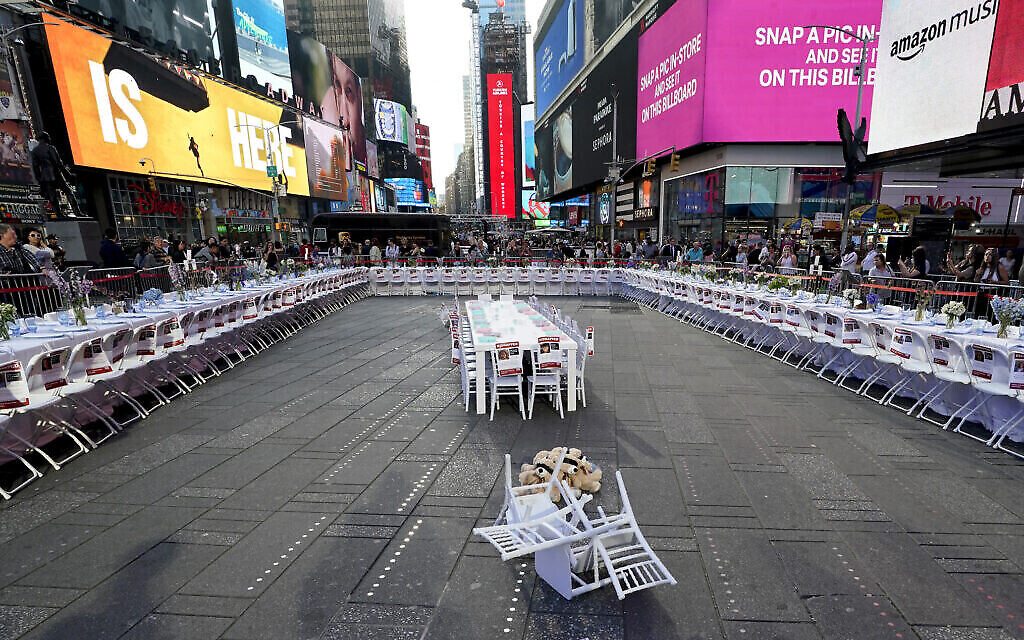 Le Conseil israélo-américain, le Comité juif américain et d'autres organisations juives dévoilent une installation à Times Square, le 26 octobre 2023, fait d'une table de Shabbat de 222 couverts avec une chaise et une assiette pour chacun des otages du Hamas. (Crédit : TIMOTHY A. CLARY / AFP)