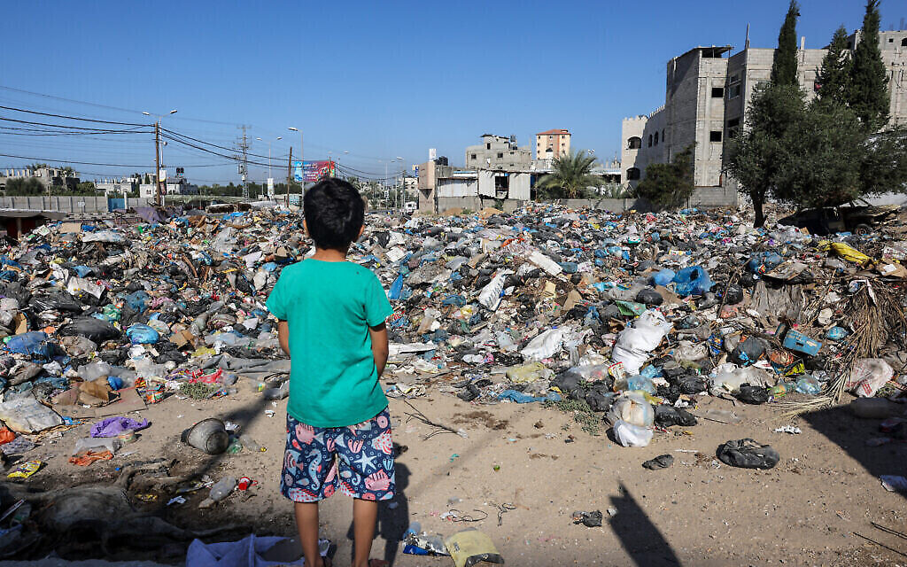 Un garçon regarde des tas d'ordures qui jonchent le camp de réfugiés de Bureij, dans le centre de la bande de Gaza, le 4 novembre 2023, pendant la guerre entre Israël et le Hamas. (Crédit : Mohammed Abed / AFP)